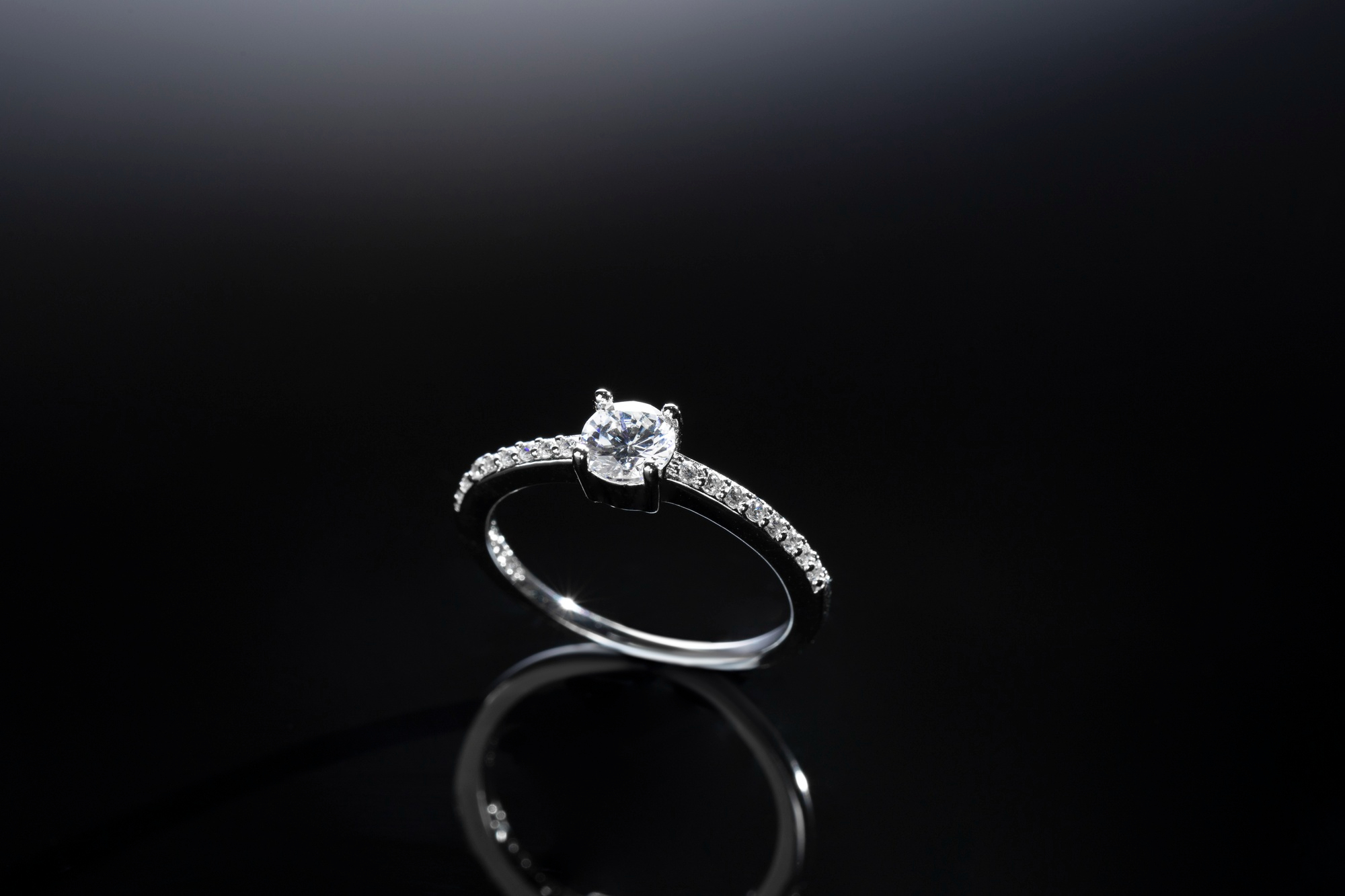 Diamond solitaire engagement ring on black surface