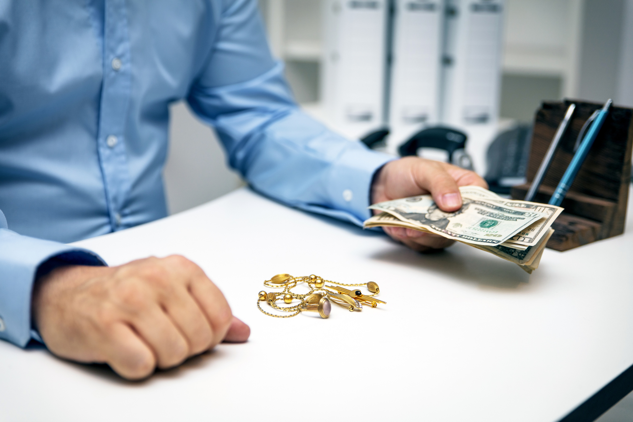 Person handing cash near keys and jewelry