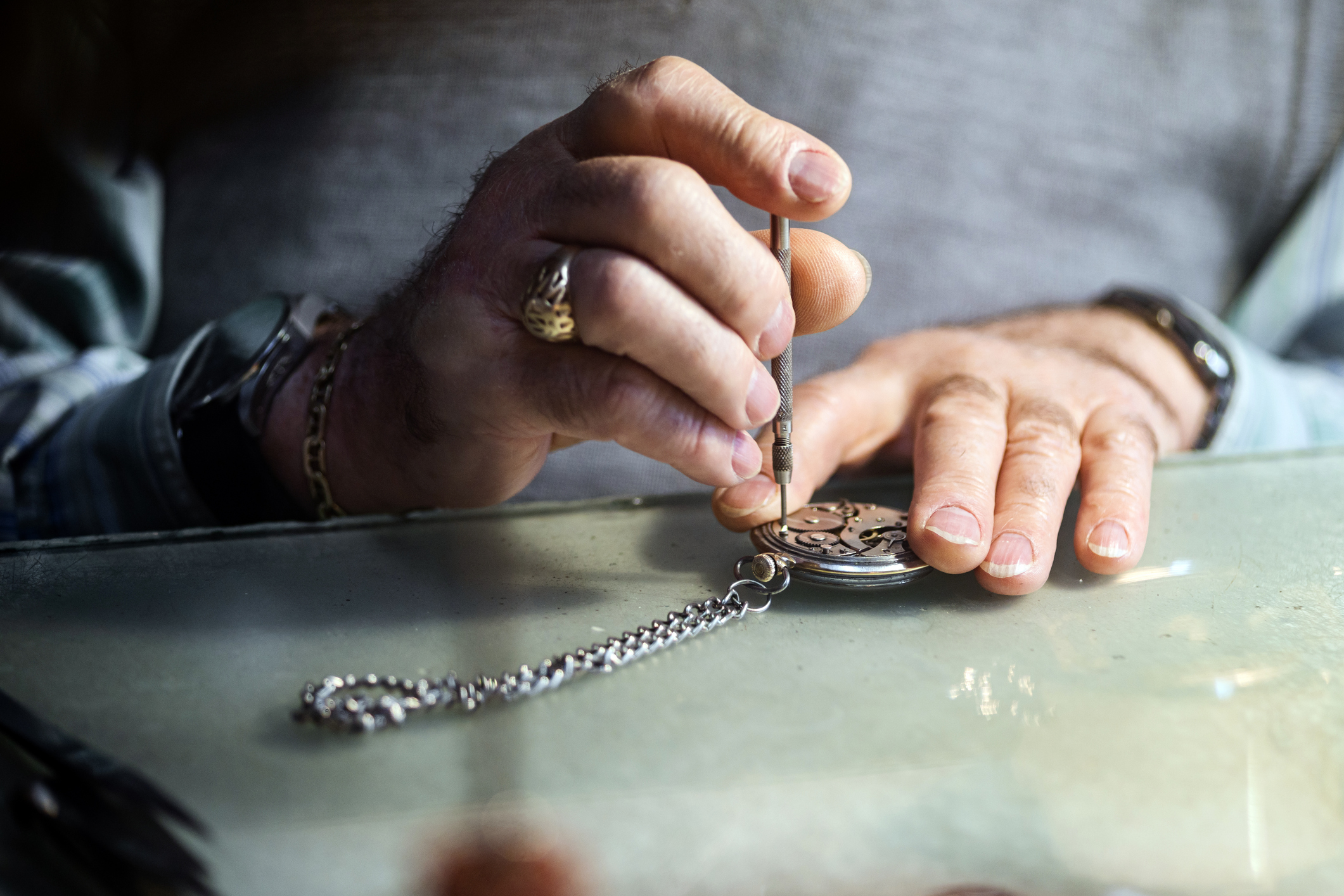 Hands repairing pocket watch with screwdriver