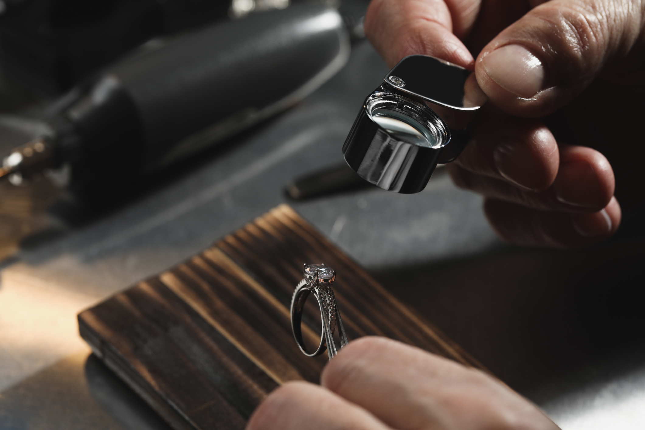 Jeweler inspecting diamond engagement ring with loupe