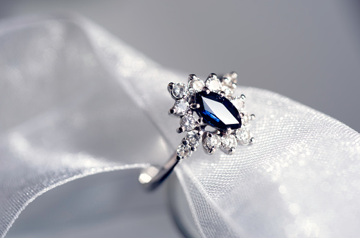 Sapphire and diamond halo ring on white ribbon