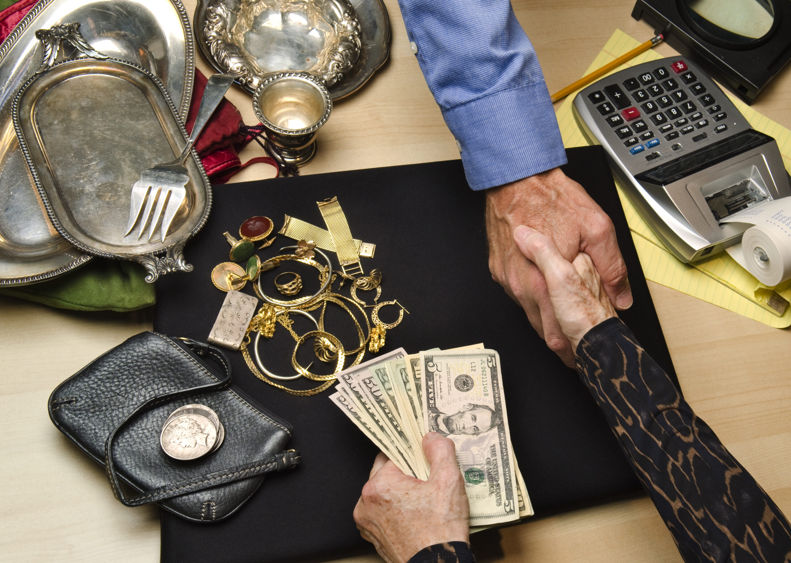Pawnshop handshake over cash and jewelry